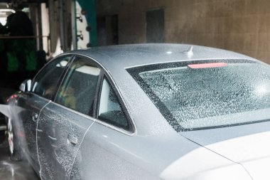selective focus of vehicle with white foam in car wash  clipart