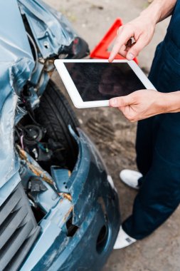 cropped view of man pointing with finger at digital tablet with blank screen near damaged car  clipart