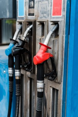 selective focus of red and blue gas pumps with fuel on gas station  clipart