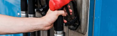panoramic shot of man holding red gas pump on gas station  clipart