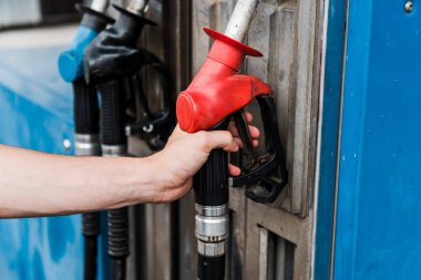 selective focus of man holding red gas pump on gas station  clipart