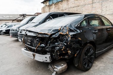 selective focus of damaged black vehicle after car accident near modern automobiles clipart