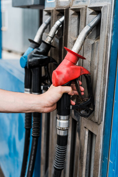 cropped view of man holding red gas pump on gas station 