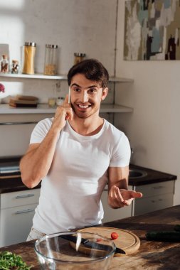 mutfakta kiraz domates keserken akıllı telefon konuşurken gülümseyen adam