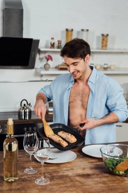 mutfakta balık ile kızartma tavası tutan seksi gülümseyen adam