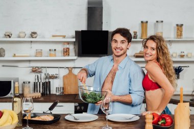 seksi çift birlikte yemek ve mutfakta gülümseyerek