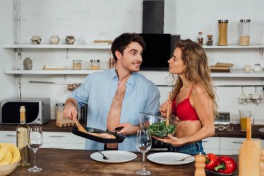 seksi çift birlikte yemek ve mutfakta gülümseyerek