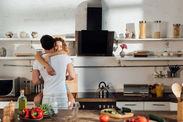 キッチンで食べ物とテーブルの近くに抱きしめるセクシーなカップル — ストック写真