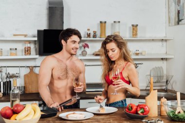 seksi çift gıda ile masanın yanında duran ve şarap bardakları tutarak