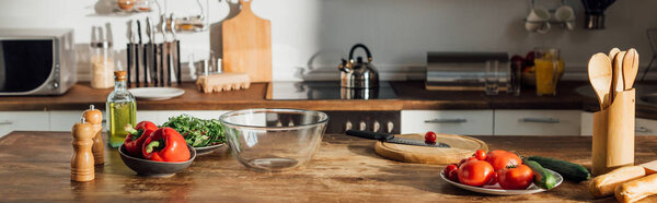 панорамный снимок свежих овощей и кухонной утвари на столе на кухне
