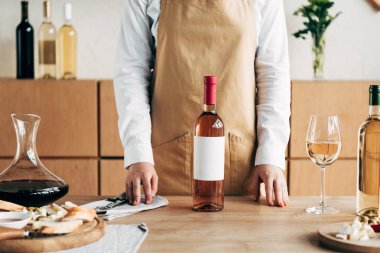 şarap şişeleri ile masa yakınında apron ayakta Sommelier kısmi görünümü