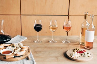 şarap gözlükleri, ahşap masada şarap ve yiyecek şişeleri