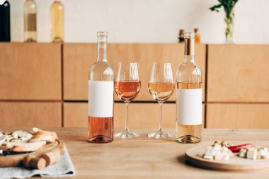 selective focus of food, wine glasses and bottles on wooden table clipart