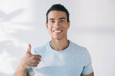 handsome man showing thumb up, smiling and looking at camera clipart