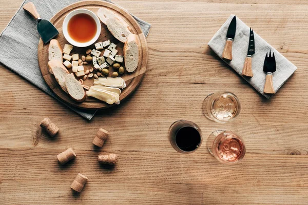 木製の表面にワイングラス ソース チーズ オリーブ コルク 調理器具のトップビュー — ストック写真