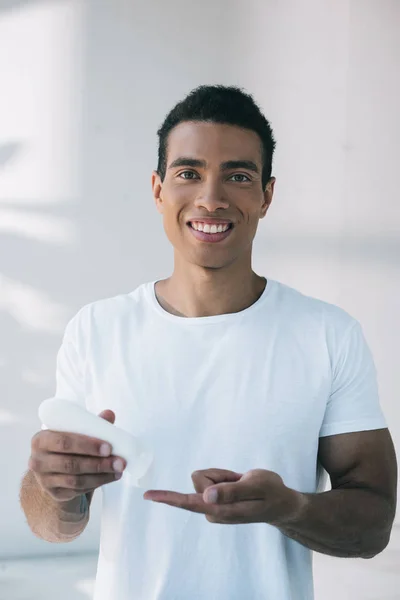 Knappe Jonge Man Putting Cosmetische Crème Vinger Van Witte Fles — Stockfoto