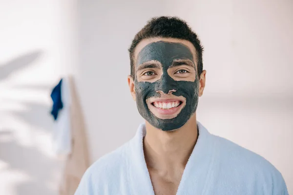 Joven Guapo Albornoz Con Máscara Arcilla Gris Cara Sonriendo Mirando —  Fotos de Stock