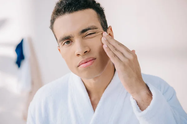 Serious Young Man Bathrobe Touching Face Looking Camera — Stock Photo, Image
