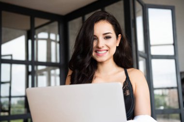 siyah iç çamaşırı seksi kız ve beyaz gömlek gülümseyen ve kamera bakarak dizüstü bilgisayar kullanarak
