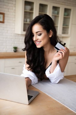 siyah iç çamaşırı seksi kız ve dizüstü bilgisayar kullanarak beyaz gömlek ve gülümsemek kredi kartı tutarken