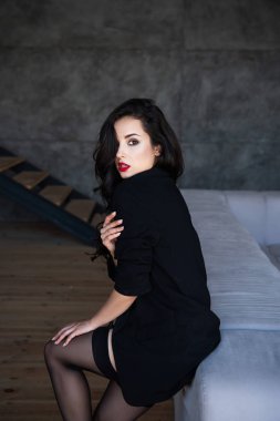Siyah ceket ile seksi kız kanepede oturan ve kamera bakıyor