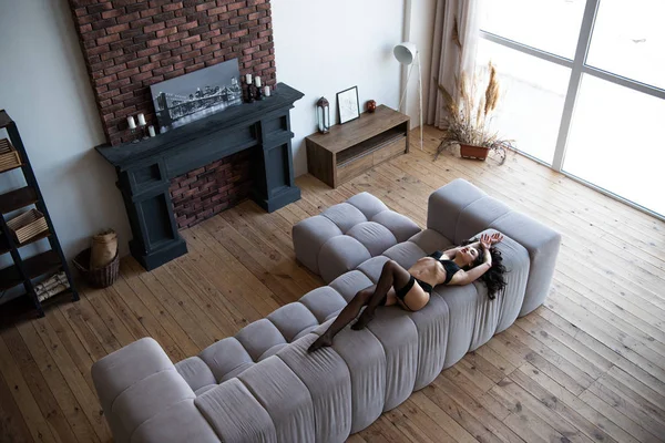 リビングルームのソファに横たわる黒い下着のセクシーな女の子の高角図 — ストック写真