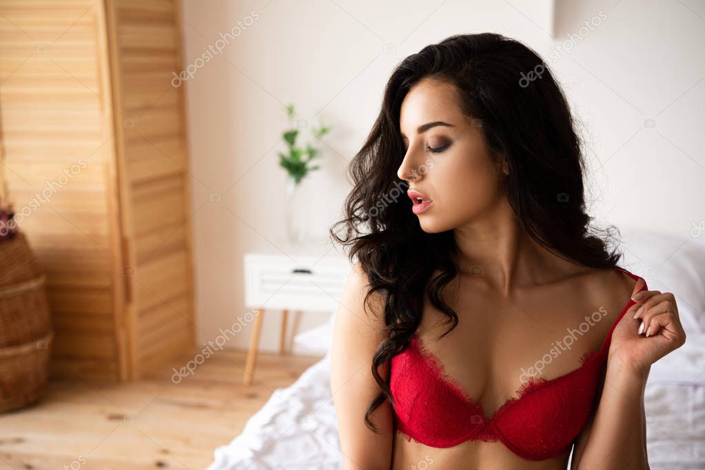 sexy young girl in red underwear sitting on bed with closed eyes
