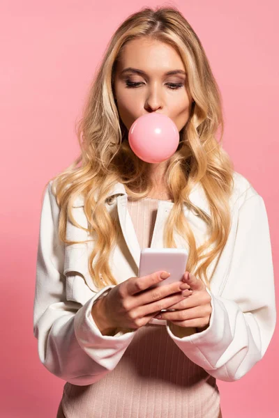 Blond Młoda Kobieta Różowy Bubble Gum Ustach Pomocą Smartphone Białym — Zdjęcie stockowe