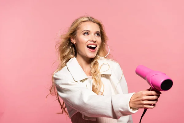 Glimlachend Mooie Blonde Vrouw Met Haardroger Geïsoleerd Roze — Stockfoto
