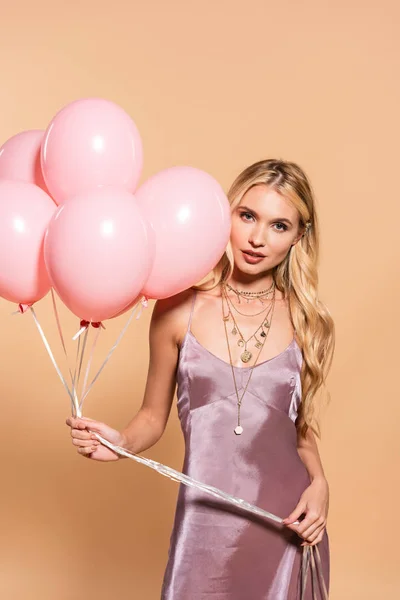 Elegancka Blondynka Fioletowej Satynowej Sukni Naszyjnik Trzyma Różowe Balony Beżu — Zdjęcie stockowe