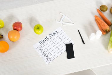 yemek planı üst görünümü, boş ekranlı akıllı telefon, haplar, kaliper, kalem ve ahşap yüzeyde taze gıda