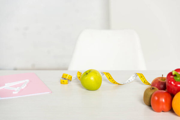 folder, measure tape and fresh fruits and vegetables on table
