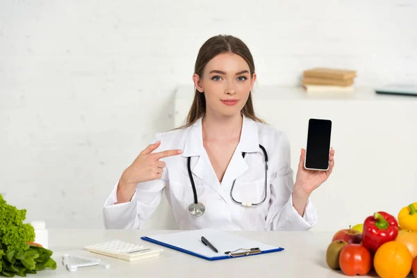 Beyaz Önlüklü Diyetisyen Boş Ekranlı Akıllı Telefon Tutan Işyerinde Parmakla — Stok fotoğraf