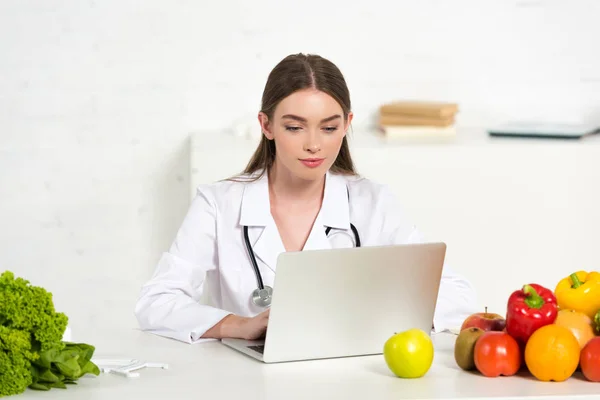 Focused Dietitian White Coat Using Laptop Workplace Fruits Vegetables — Stock Photo, Image