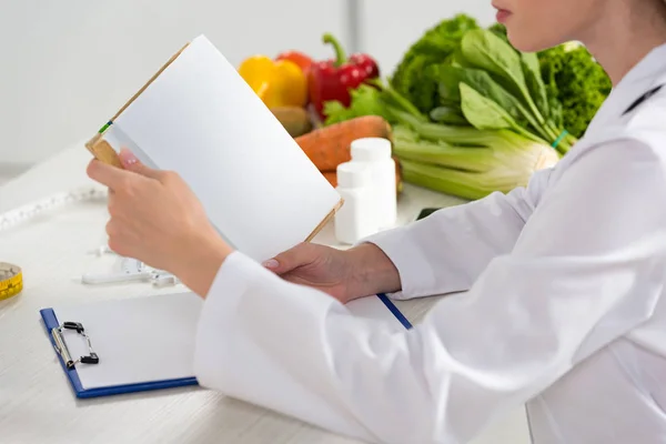 Cropped View Dietitian White Coat Reading Book Workplace — Stock Photo, Image