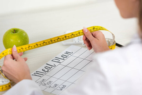 cropped view of dietitian holding measure tape at workplace