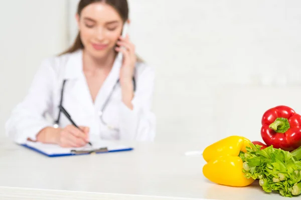 Selective Focus Dietitian White Coat Writing Clipboard Talking Smartphone Workplace — Stock Photo, Image