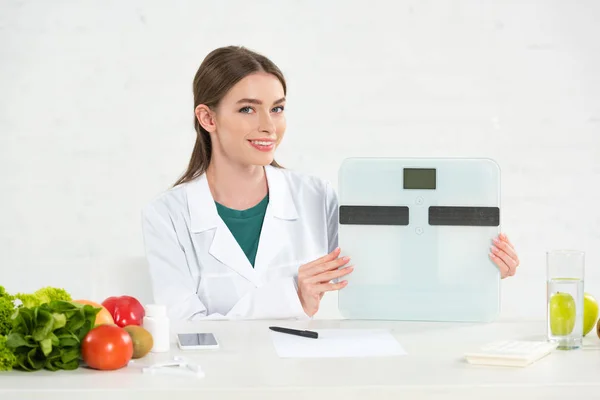 Smiling Dietitian White Coat Holding Digital Scales Workplace — Stock Photo, Image