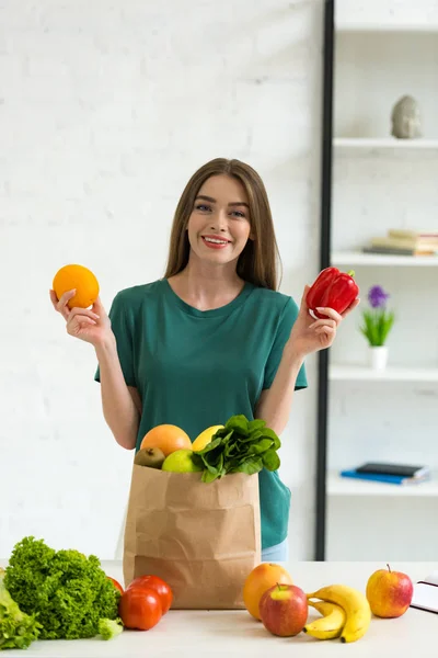 Smiling Young Woman Holding Orange Bell Pepper While Standing Paper — Stock Photo, Image