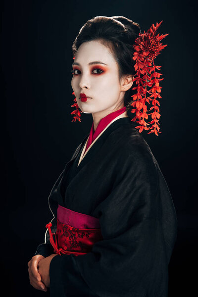 geisha in black and red kimono and flowers in hair isolated on black