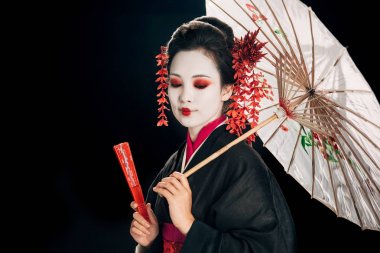 geleneksel asya şemsiye si ve el fan tutan saç kırmızı çiçeklerile siyah kimono güzel geyşa ve siyah izole aşağı bakıyor