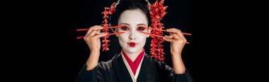 siyah, panoramik çekim izole gözleri yakınında çubukları tutan saç kırmızı çiçekler ile siyah kimono güzel geyşa