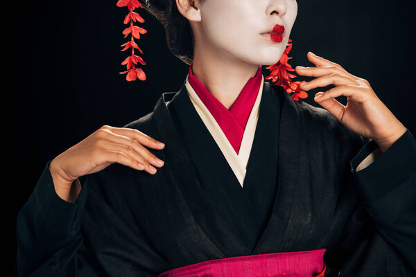 partial view of beautiful geisha in black and red kimono gesturing isolated on black