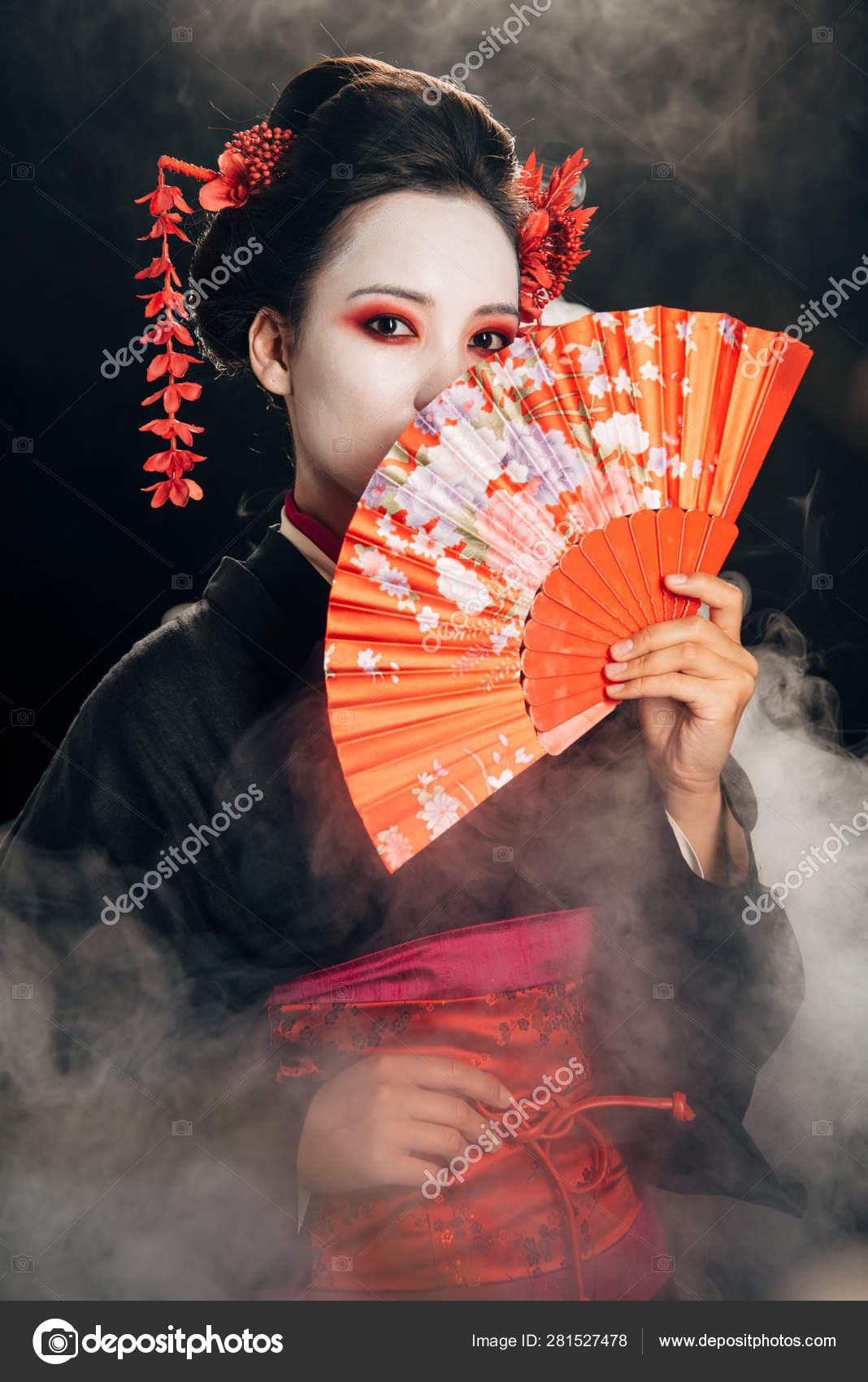 美丽的艺伎在黑色和服与花在头发拿着手扇在烟雾 图库照片 C Igorvetushko