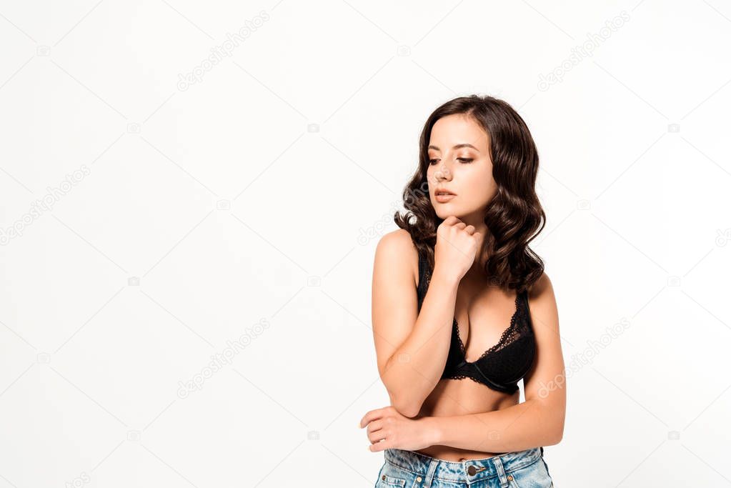 thoughtful girl touching face while standing on white 