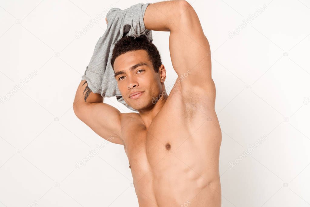 sexy mixed race man undressing and looking at camera on white 