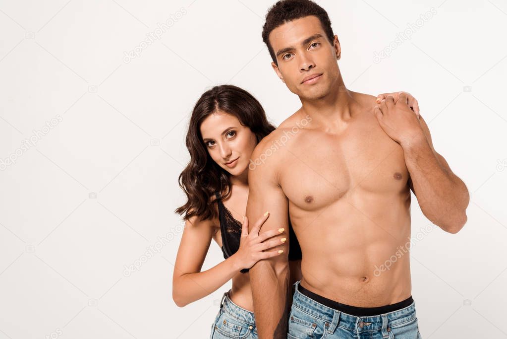 beautiful girl in lace bra standing with shirtless mixed race man isolated on white 