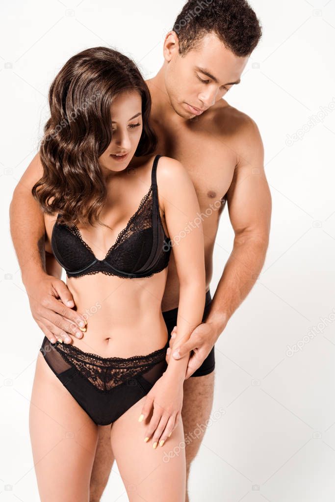 shirtless bi-racial man touching sexy woman in black underwear isolated on white 
