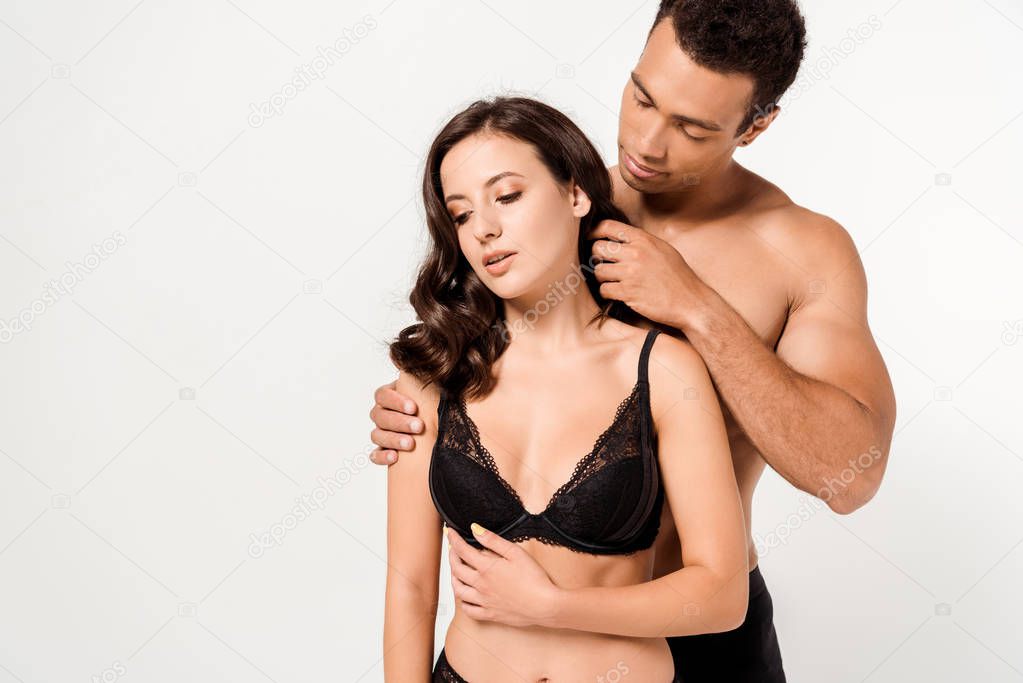 shirtless bi-racial man touching young woman in black underwear isolated on white 
