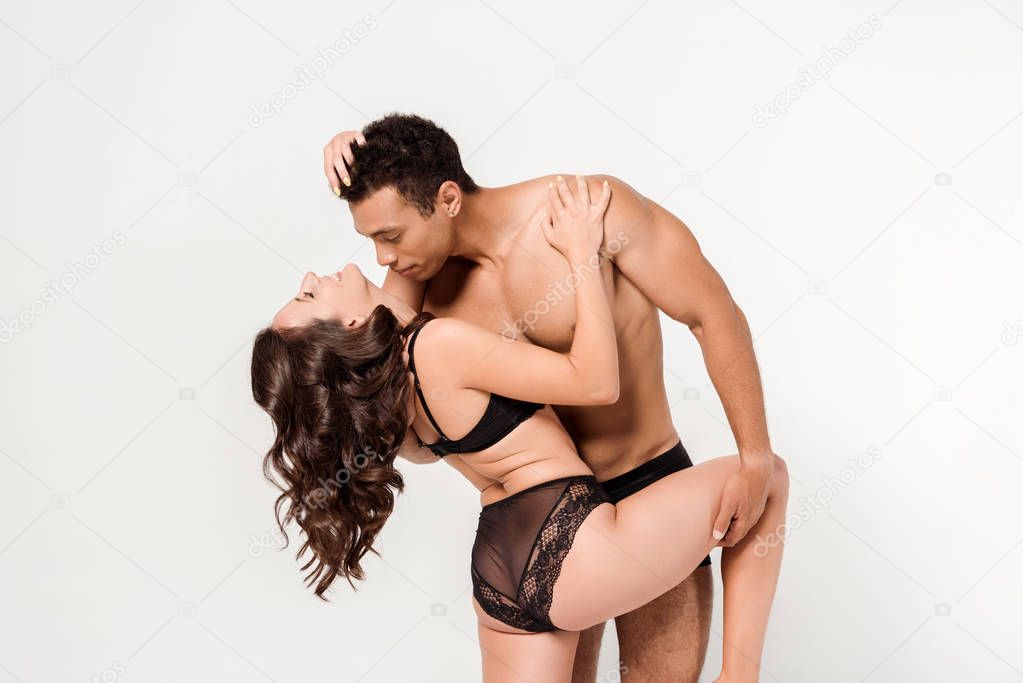 handsome mixed race man hugging cheerful girl in lace underwear isolated on white 